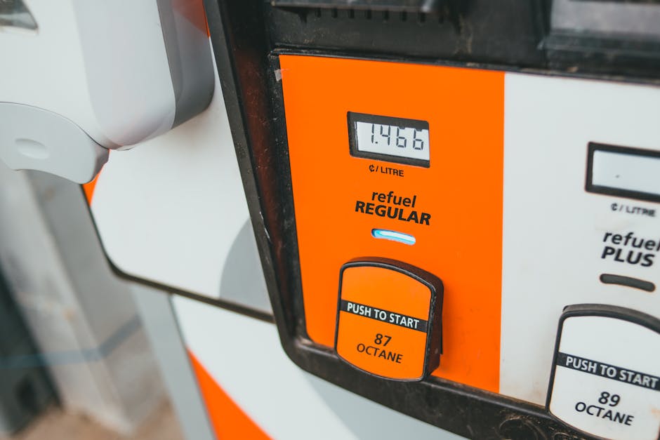 Close-up view of a modern fuel dispenser showing a digital display indicating a quantity of 1.4466 liters of fuel used, with the words 'refuel REGULAR' printed beneath and a small blue indicator light. Below the display is a rectangular black button with orange accents labeled 'PUSH TO START' and the octane rating '87 OCTANE' in bold black text. To the right, part of another fuel pump with additional octane options is visible. The equipment is set against a background that suggests an outdoor fuel station environment, with the focus primarily on the fuel dispenser's controls and display panel. The materials appear to be predominantly plastic and metal, with a finish that is clean and well-maintained, suitable for professional fuel or alternative fuel supply in a public or private setting. This image aligns with service contexts involving alternative waste handling, vehicle refueling, or private fuel station management, often associated with complementary waste management services like rubbish removal for convenience on-site or elsewhere.